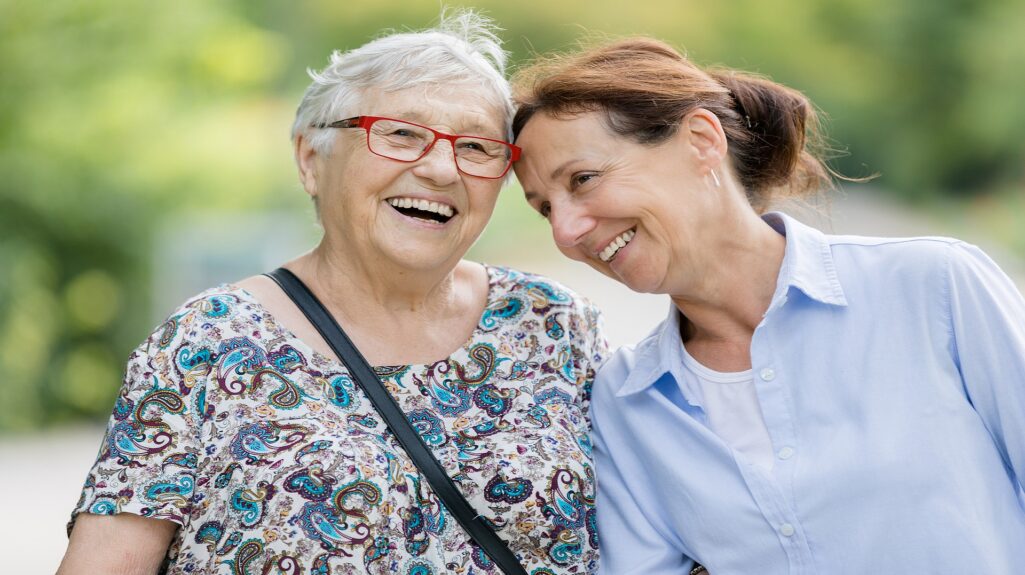 Happy Senior Woman And Caregiver Walking Outdoors